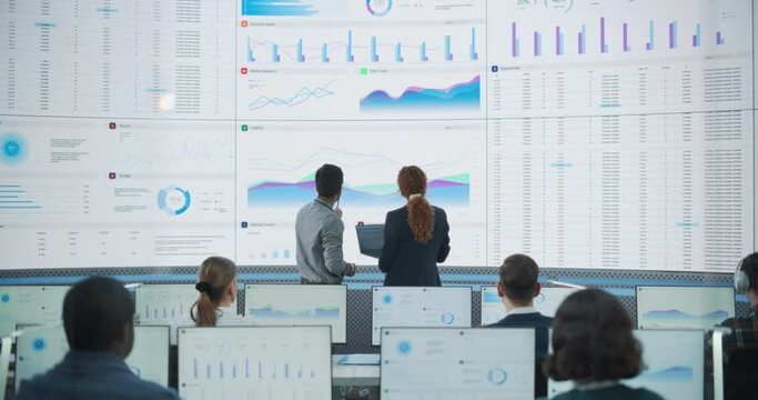Wide Zoom Out Back Shot Of Diverse Male And Female Risk Managers Analyzing Data On Digital Screen In Monitoring Room. Multiethnic Employees Working On Computers For Succesful Consulting Company