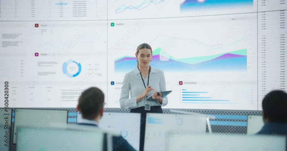 Poster Caucasian Female Project Manager With Tablet Computer Is Giving Presentation To Diverse Employees In Front of Big Digital Screen In Monitoring Room. Team Of Data Scientists Listening To New Objectives