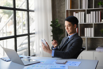 Young business man working at office with laptop, tablet and taking notes on the paper..