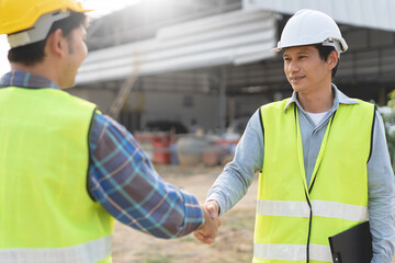 construction worker and contractor. Client shaking hands with team builder in the factory construction site.