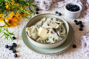 Dumplings with blueberries in a beautiful plate with butter on a white background. Dumplings with berries for breakfast or lunch. Close-up.