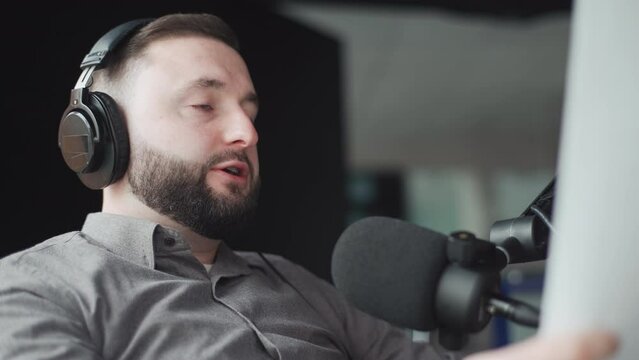 Portrait of a young handsome radio host in headphones speaking into a microphone during a radio broadcast.
