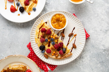 Top view of crepes with berries and jam on plate breakfast food on light surface