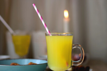 Plate of chocolate pralines, bowl of cookies, cups of tea, glasses of juice and lit candles on the table. Selective focus.
