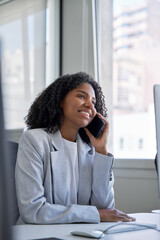 Obraz premium Vertical shot of African American businesswoman having call on phone, talking on cellphone in office. Young woman have communication with business partners, clients, make technical support, consulting
