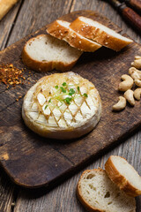 Baked Camembert cheese on a wooden board. Baguette