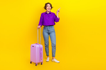 Full body cadre of young business woman first flight point finger mockup airport registration table isolated on yellow color background