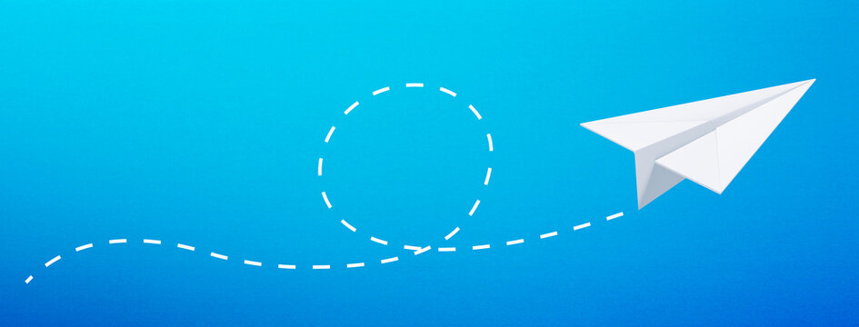 Paper airplane with a dashed line it on blue background