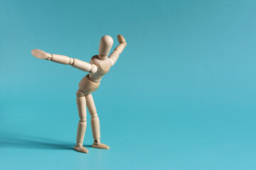A wooden man does exercises by leaning forward and spreading his arms to the sides