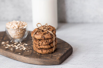 Organic natural cow's milk in a glass bottle, oatmeal and oatmeal cookies on a stylish wooden board on a stone table. Natural eco-friendly products.