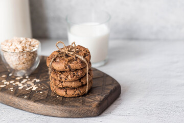 Organic natural cow's milk in a glass bottle, oatmeal and oatmeal cookies on a stylish wooden board on a stone table. Natural eco-friendly products.