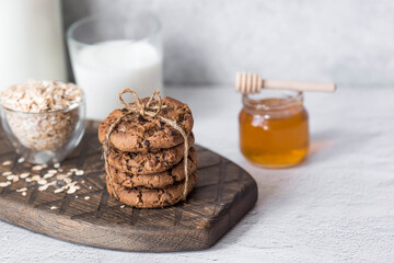 Organic natural cow's milk in a glass bottle, oatmeal, honey and oatmeal cookies on a stylish wooden board on a stone table. Natural eco-friendly products.