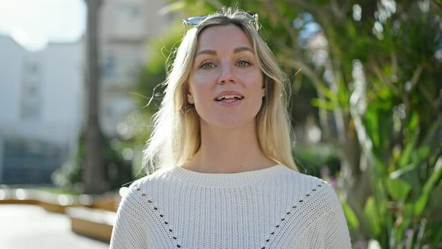 Young blonde woman smiling confident speaking at park