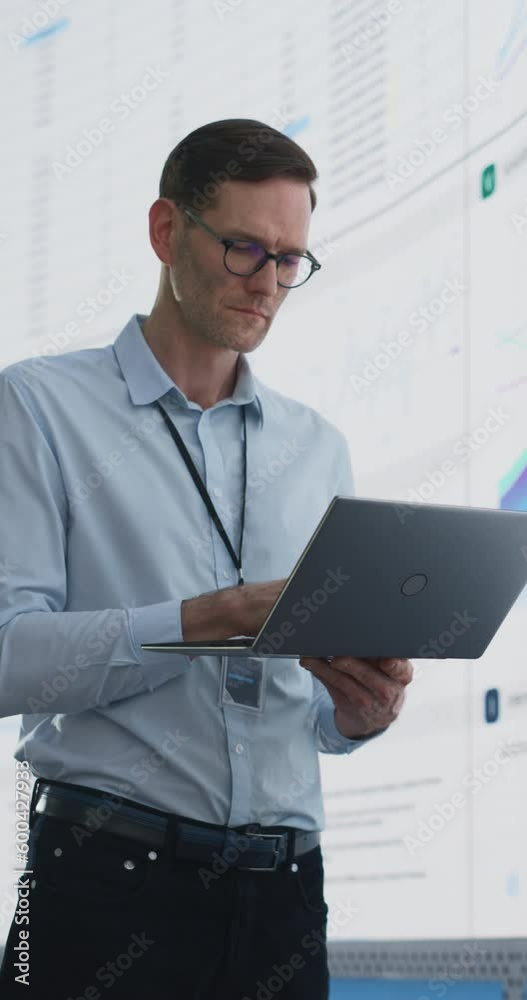 Aufkleber vertical screen: caucasian male business analyst holding laptop computer and standing next to big le
