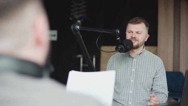 Two podcasters laughing and having fun in the studio. Two happy young people are doing a live audio broadcast together.