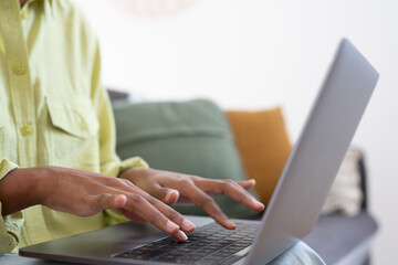 African female employee working at laptop, typing on keyboard. Woman hands close up. Businesswoman in casual, professional working at table, using online app, chatting, writing article. Cropped shot.