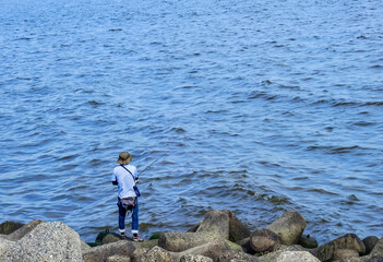 Fototapeta na wymiar 海の磯で魚釣りをする人