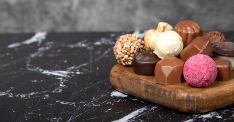 Obraz na płótnie Canvas Praline Chocolate. Assorted truffles or praline chocolates on wood serving board. Copy space. Empty space for text