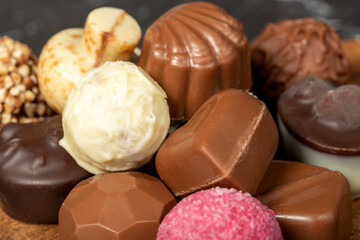 Obraz na płótnie Canvas Praline Chocolate. Assorted truffles or praline chocolates on wood serving board. Close up