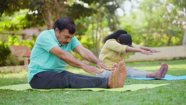 Indain senior couple at morning doing yoga at park - concept of healthy active lifestyle, outdoor fitness and wellness