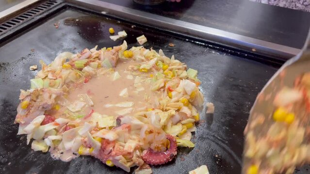 鉄板の上でもんじゃ焼きを焼く