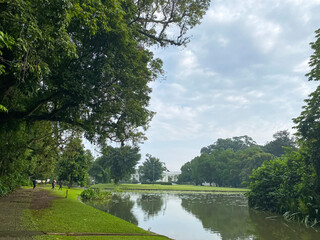 Forestry lake against cloudy sky with greenery grass at Raya Bogor  park.
