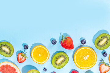 Summer vitamin food concept, various fruit and berries mango peach mint plum apricots blueberry currant, creative flat lay on light blue background top view copy space