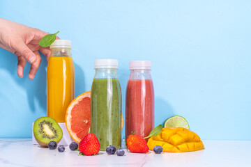 Fototapeta na wymiar Green, orange and red smoothie in portion bottles, Mix of colourful healthy smoothie or juice drinks of different fruits: orange, grapefruit, lime, kivi, strawberry, with ingredients