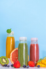  Green, orange and red smoothie in portion bottles, Mix of colourful healthy smoothie or juice drinks of different  fruits: orange, grapefruit, lime, kivi, strawberry, with ingredients