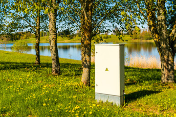 Locker of electric system under a trees. Outdoor electric high voltage distribution cabinet in a park.