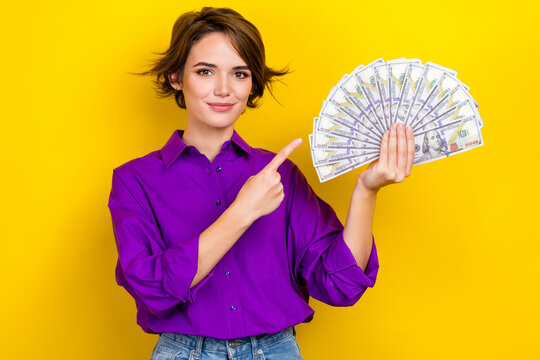 Photo portrait of lovely young lady point money banknotes fan wear trendy violet smart casual garment isolated on yellow color background