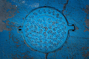 Bouche d'égout sur la route, bitume et peinture bleu au sol