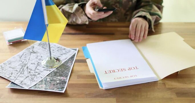 Military taking photo on mobile phone of document with inscription top secret and counteroffensive during war between Ukraine and Russia 4k movie slow motion. Betrayal and espionage during military