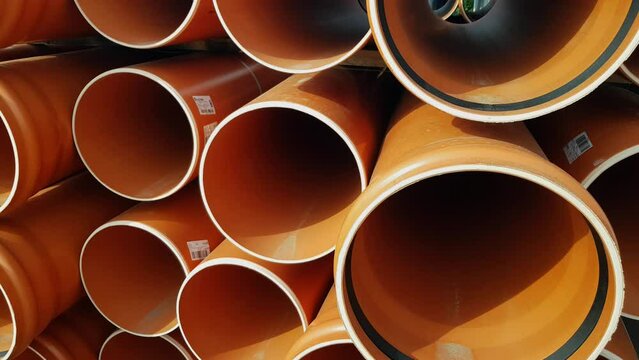 A large pile of plastic orange sewage pipes used in the city sewage system	