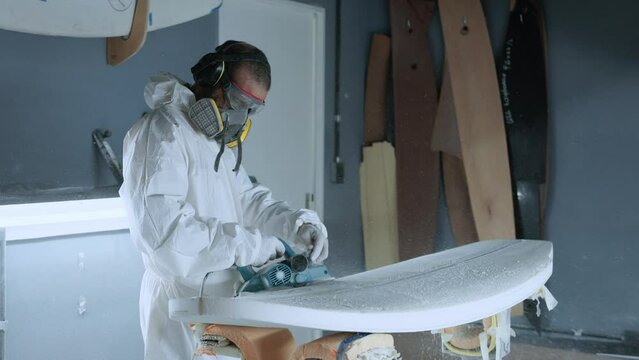 Professional master polishing surfboard in workshop