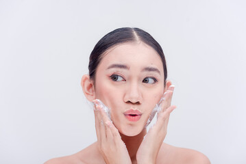 Female commercial model applying facial wash for her skin care routine advertisement studio shoot with plain white backdrop.