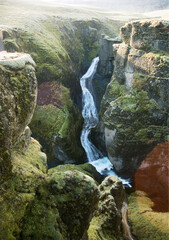 A waterfall flowing down into a deep canyon in the middle of iceland.
