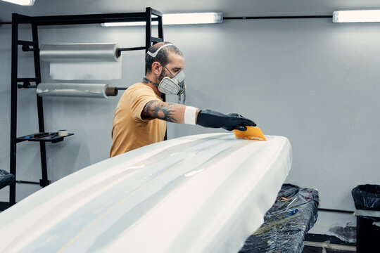 Serious man attaching film on surfboard - Powered by Adobe