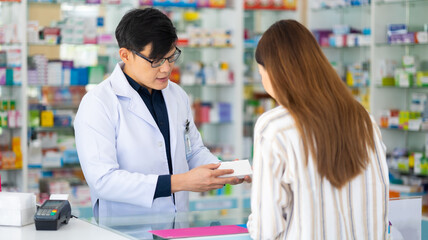 Asian male pharmacists explaining how to take drugs to treat diseases correctly at Pharmacy Drugstore.  Health and wellness center