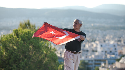 Patriotic senior man celebrates Turkish independence day with a national flag in his hands. Constitution and Citizenship Day.