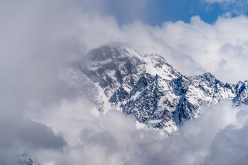 Fototapeta na wymiar Mountain peak in clouds. Top of snowy rock in Georgia.