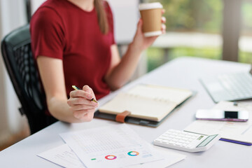 Concept of business office woman working,Closeup businesswoman checking her invesment plan with analyzing document and business investment graph data by using calculator and laptop