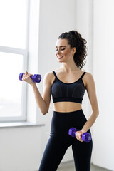 Fototapeta na wymiar fitness, sport and healthy lifestyle concept. Smiling young woman with dumbbells exercising at home