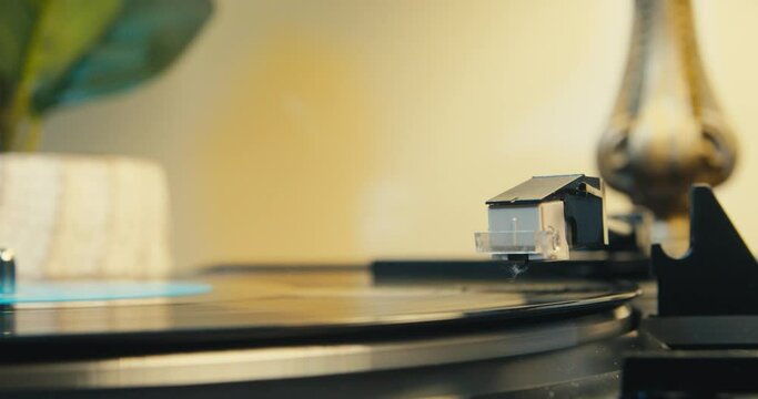 Record Player Vinyl Playing Gramophone. Vinyl Record on Spinning on a Vintage Turntable, Listening to Music on a Gramophone. Retro Music Player on Living Room Home Background in Evening. 