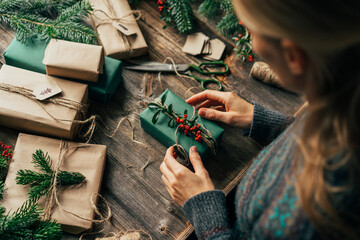 Woman wrapping and decorating Christmas gift boxes