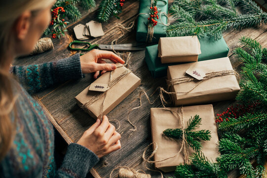 Woman Wrapping Family Christmas Presents In Craft Paper