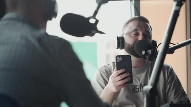 Two podcasters laughing and having fun in the studio. Two happy young people are doing a live audio broadcast together.