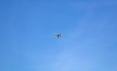 The plane flies high in the blue sky with small clouds