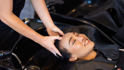 Fototapeta na wymiar hairdresser washing hair of beautiful asian woman in beauty salon small business owner