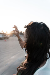 A young Hispanic woman is admiring a found seashell during sunset